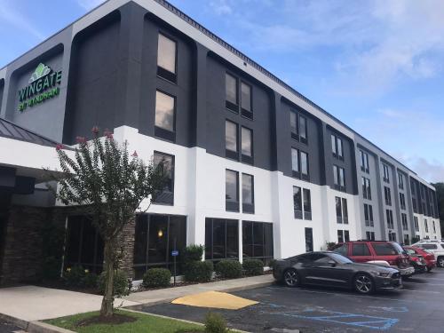 a black and white building with cars parked in a parking lot at Wingate by Wyndham Charleston Coliseum in Charleston