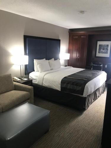a hotel room with a large bed and a couch at Wingate by Wyndham Charleston Coliseum in Charleston
