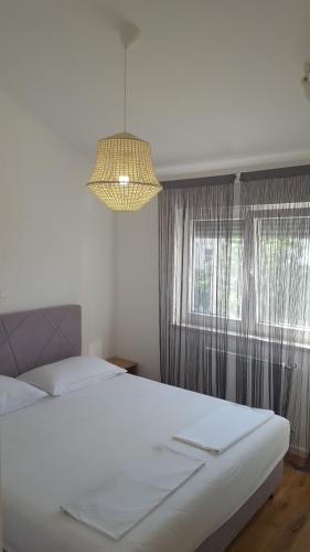 a bedroom with a large white bed and a window at Apartments Ivanov in Zadar