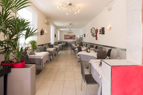 un restaurante con mesas, sillas y plantas en Hotel Atene, en Lido di Jesolo