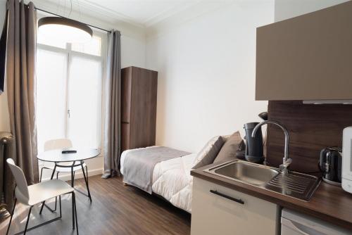 a kitchen with a sink and a bed in a room at Les cles du 27 Paris in Paris