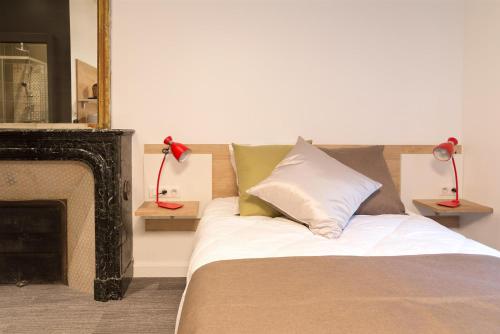 a bedroom with a bed and a fireplace with two lamps at Les cles du 27 Paris in Paris