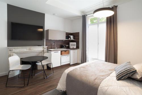 a bedroom with a bed and a table and a kitchen at Les cles du 27 Paris in Paris