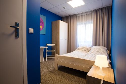 1 dormitorio con cama y pared azul en Moon Hostel Poznań, en Poznan