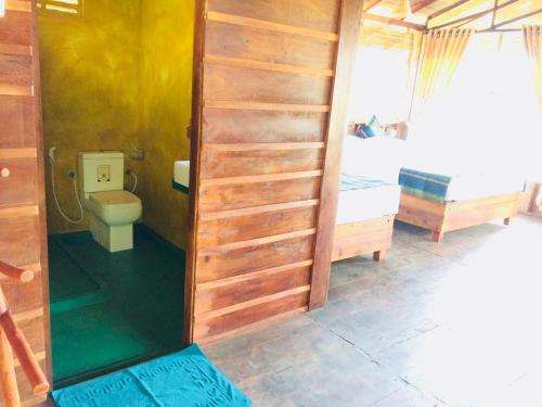 a bathroom with a toilet and a bed in a room at Chena Huts Eco Resort in Sigiriya