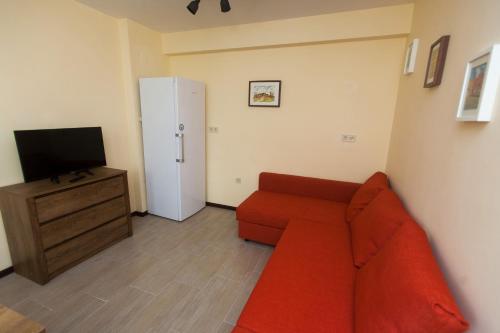 a living room with a red couch and a television at Sofia Family House - Free Parking in Sofia
