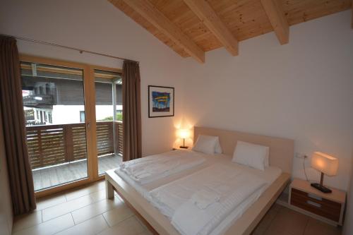 a bedroom with a large white bed and a window at Schmitten Finest Apartments by All in One Apartments in Zell am See