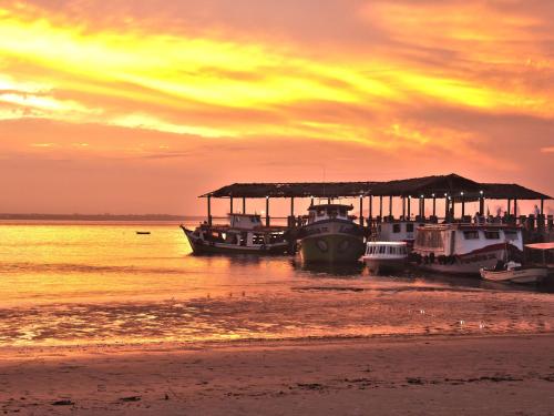 a group of boats docked on the beach at sunset at Pousada Renascer in Ilha do Mel