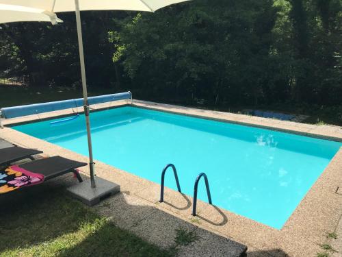 uma grande piscina azul com um guarda-sol em Casa Parentela em Ligornetto