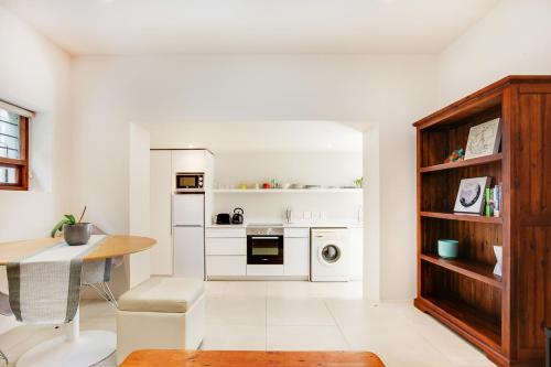 a kitchen with white appliances and a table and a dining room at Cheviot Place Garden Apartment with Private Entrance in Cape Town