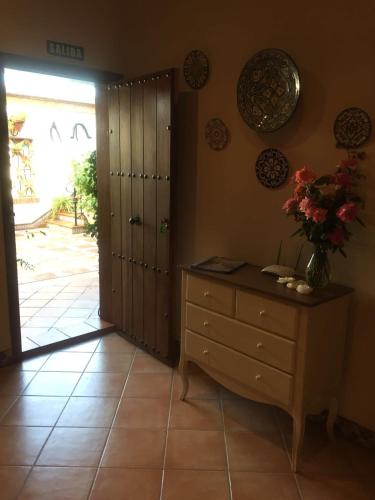 a room with a dresser with a vase of flowers on it at Hotel Rural Andalucia in Sierra de Yeguas