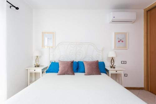 プラヤ・パライソにあるEDEN RENTALS Duplex Adeje Palaceの白いベッド(青い枕付)が備わるベッドルームです。