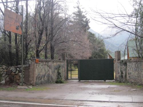 a gate to a building with a stone wall at Cabaña El Tiempo Es Arte in San José de Maipo