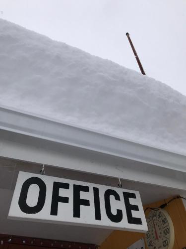 a sign on the roof of a store with snow on it at Snowdon Chalet Motel in Londonderry