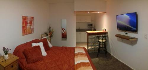 1 dormitorio con cama roja y cocina en Oficina 38, en Punta del Este