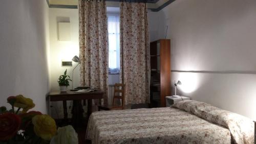 una camera con letto, scrivania e finestra di Vacantara a Pisa