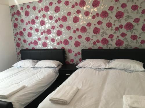 two beds in a room with flowers on the wall at Brookfield’s Apartment in Clacton-on-Sea