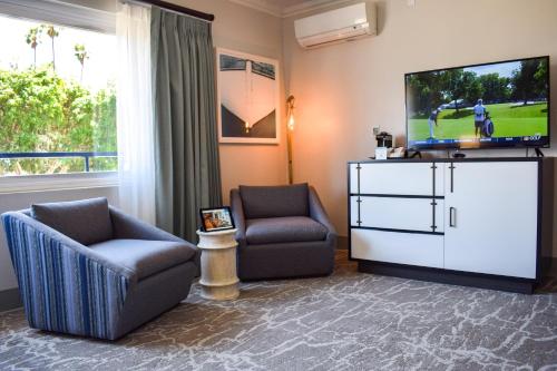 a living room with two chairs and a flat screen tv at Beachside Inn in Santa Barbara