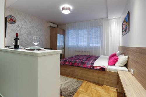 Schlafzimmer mit einem Bett und einem Glas Wein in der Unterkunft Apartment Promenada 30 in Novi Sad