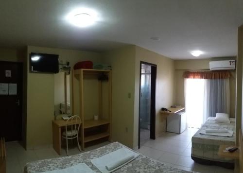 a hotel room with two beds and a television at Hotel Da Vila in Joinville