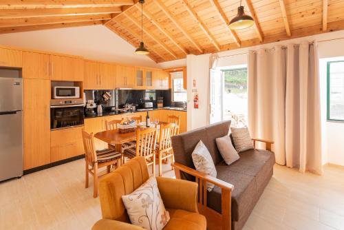 a kitchen and living room with a couch and a table at Casa da Figueirinha in Calheta de Nesquim