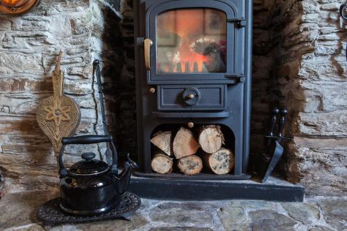 a wood stove with logs and a tea kettle at Charming Devon Cottage near Quay-Rain Shower, Restaurants & Free Parking in Kingsbridge