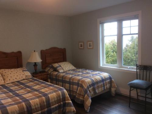 een slaapkamer met 2 bedden en een raam bij Condo Lac Archambault 298 in Saint-Donat-de-Montcalm