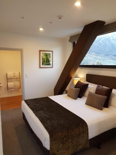 a bedroom with a large bed with a large window at Wyndham Garden Remarkables Park Queenstown in Queenstown
