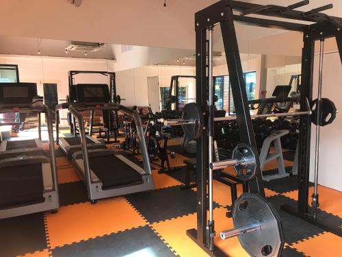 a gym with several tread machines and a mirror at V20 Boutique Jacuzzi Hotel in Bangkok
