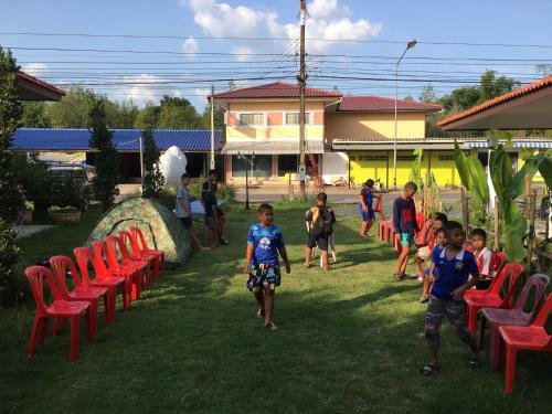 a group of children walking around in a yard with red chairs at Baan Suan Kru Kob in Ban Ko Maphang