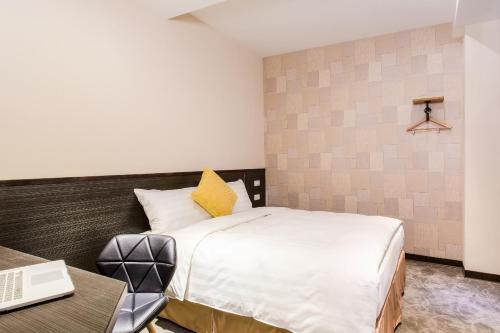 a bedroom with a bed and a desk and a laptop at RF Hotel  Linsen in Taipei