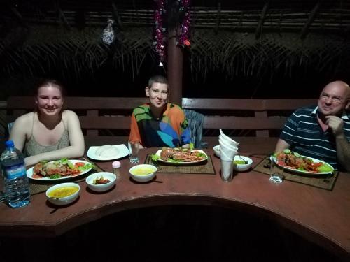 a group of people sitting at a table with plates of food at Dolphin Village in Kalpitiya