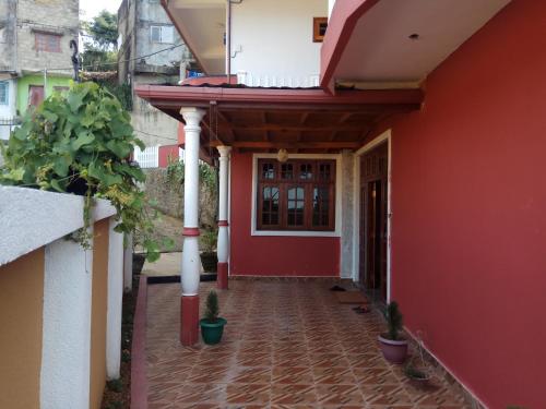 a red house with a red wall and a door at RIO Homestay in Haputale