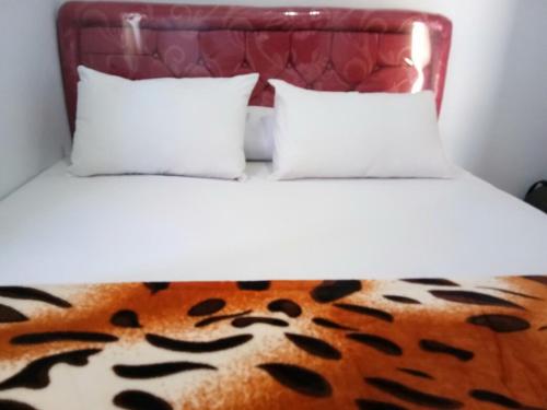 ein Bett mit zwei Kissen und einer Decke mit Tigerdruck in der Unterkunft Agung Safira Homestay in Bromo