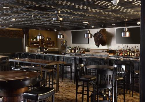 a bar with wooden tables and chairs in a restaurant at Stoney Creek Hotel Tulsa - Broken Arrow in Broken Arrow