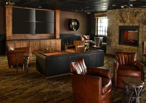a bar with brown leather chairs and a fireplace at Stoney Creek Hotel Tulsa - Broken Arrow in Broken Arrow