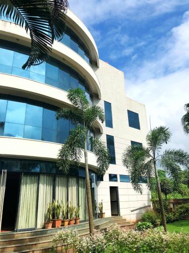 a building with palm trees in front of it at Pai Resort in Belgaum