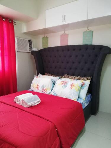 a red bed with a black head board and pillows at Nica's Place Property Management Services at Horizons 101 Condominium in Cebu City