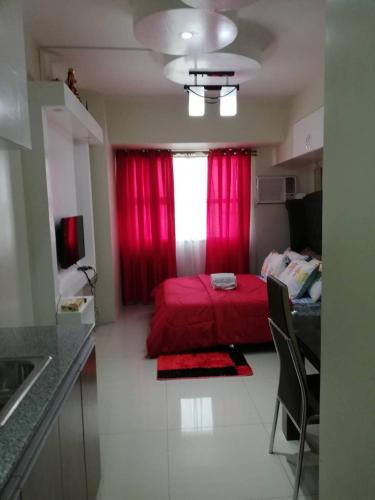 a bedroom with a red bed and a window at Nica's Place Property Management Services at Horizons 101 Condominium in Cebu City
