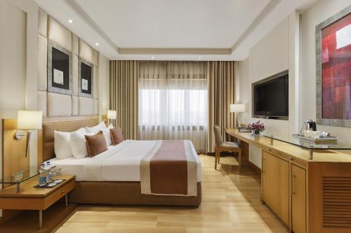 a hotel room with a bed and a desk at Park Plaza, Ludhiana in Ludhiana