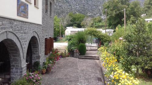 a garden with flowers and a stone building at Hotel Tymfi in Tsepelovo