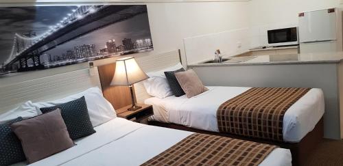 a hotel room with two beds and a kitchen at Reef Palms in Cairns