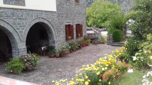 a stone building with flowers in a courtyard at Hotel Tymfi in Tsepelovo