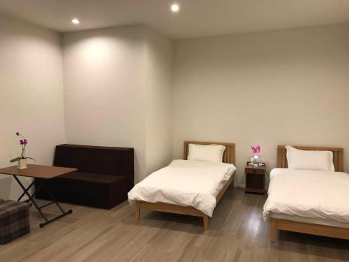 a room with two beds and a table and a desk at Kokoro no yado Mihama in Chatan