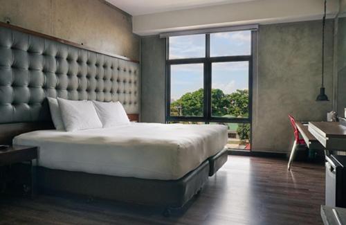 a bedroom with a large bed and a large window at The B Hotel Quezon City in Manila