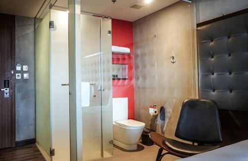 łazienka z toaletą i krzesłem w obiekcie The B Hotel Quezon City w mieście Manila