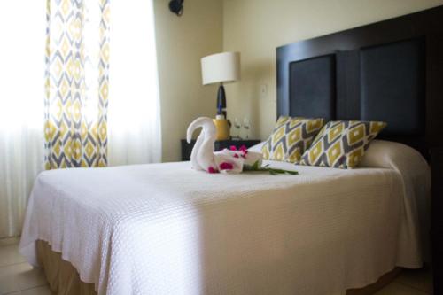 a bedroom with a white bed with a stuffed swan on it at Connie's Comfort Suites in Saint Johnʼs