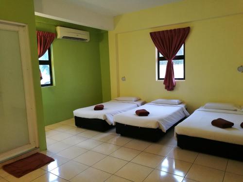 3 camas en una habitación con paredes y ventanas verdes en Walk Inn, en Miri