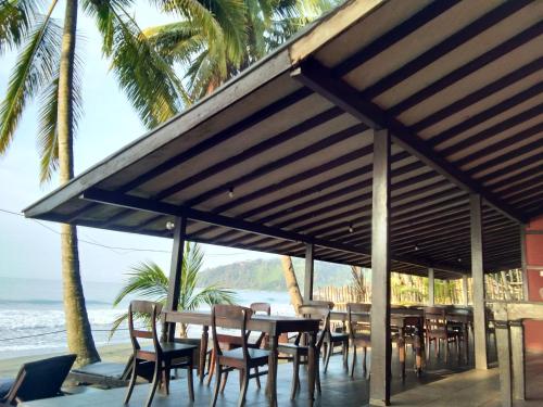 a table and chairs under a pavilion on the beach at Kuda Laut Resort in Cisolok