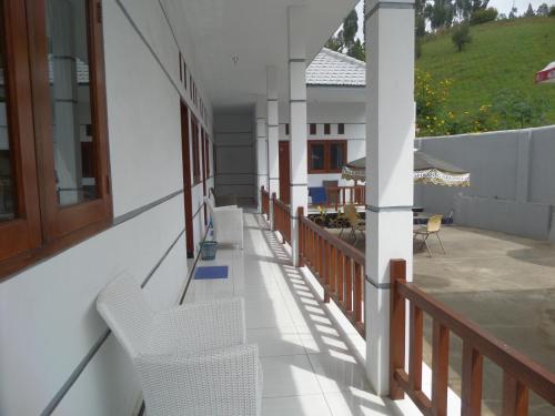a balcony of a house with white chairs and a table at Savana Guesthouse in Bromo
